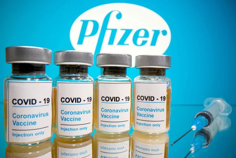 FILE PHOTO: Vials with a sticker reading, "COVID-19 / Coronavirus vaccine / Injection only" and a medical syringe are seen in front of a displayed Pfizer logo in this illustration taken October 31, 2020. REUTERS/Dado Ruvic/Illustration
