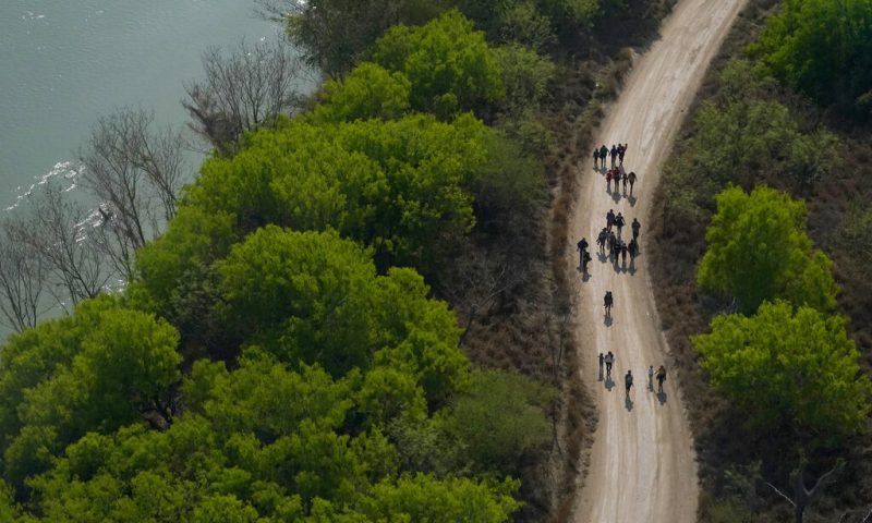 Migrants walk on a dirt road after crossing the U.S.-Mexico border, Tuesday, March 23, 2021, in Mission, Texas. (AP Photo/Julio Cortez)