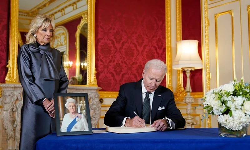President Joe Biden signs a book of condolence at Lancaster House in London, following the death of Queen Elizabeth II, Sunday, Sept. 18, 2022, as first lady Jill Biden looks on. (AP Photo/Susan Walsh)