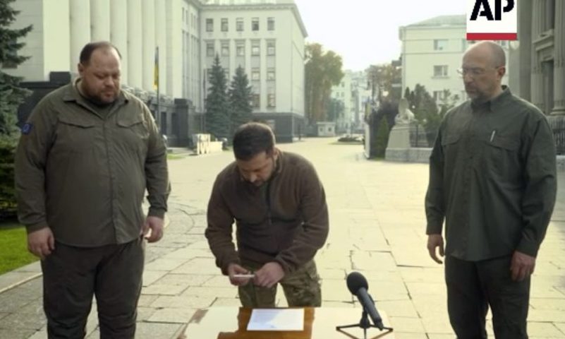 In this image taken from video, Ukrainian President Volodymyr Zelenskyy, along with Ukrainian Prime Minister Denys Shmyhal and the head of Verkhovna Rada (Supreme Council of Ukraine) Ruslan Stefanchuk, signs an application for ''accelerated accession to NATO'' in Kyiv, Ukraine, Friday Sept. 30, 2022. (AP Photo)