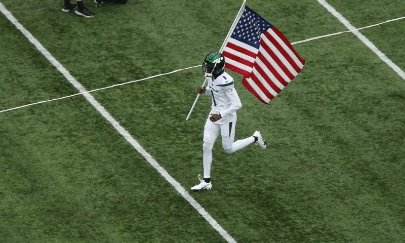 New York Jets' Sauce Gardner carries an American flag on the field before Sunday's game. (John Munson/AP)
