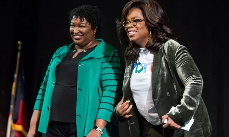 Oprah Winfrey and Georgia Democratic Gubernatorial candidate Stacey Abrams greet the audience during a town hall style event at the Cobb Civic Center on November 1, 2018 in Marietta, Georgia. Winfrey travelled to Georgia to campaign with Abrams ahead of the mid-term election. (Photo by Jessica McGowan/Getty Images)