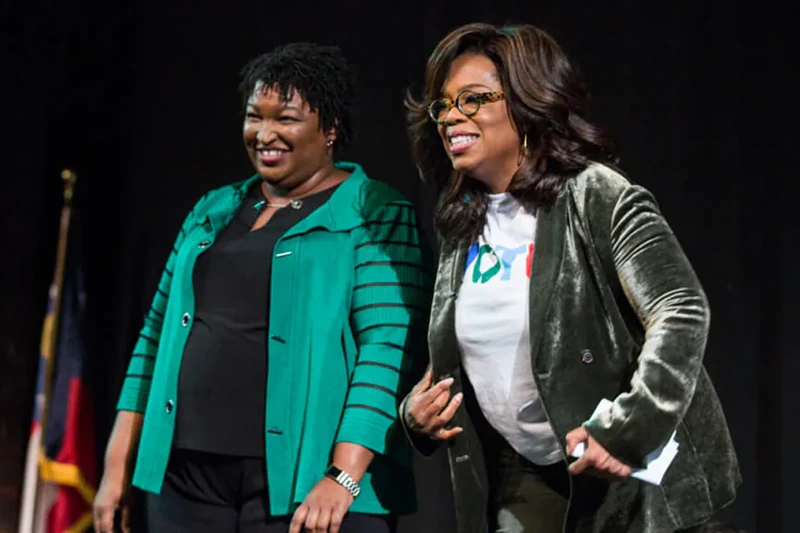 Oprah Winfrey and Georgia Democratic Gubernatorial candidate Stacey Abrams greet the audience during a town hall style event at the Cobb Civic Center on November 1, 2018 in Marietta, Georgia. Winfrey travelled to Georgia to campaign with Abrams ahead of the mid-term election. (Photo by Jessica McGowan/Getty Images)