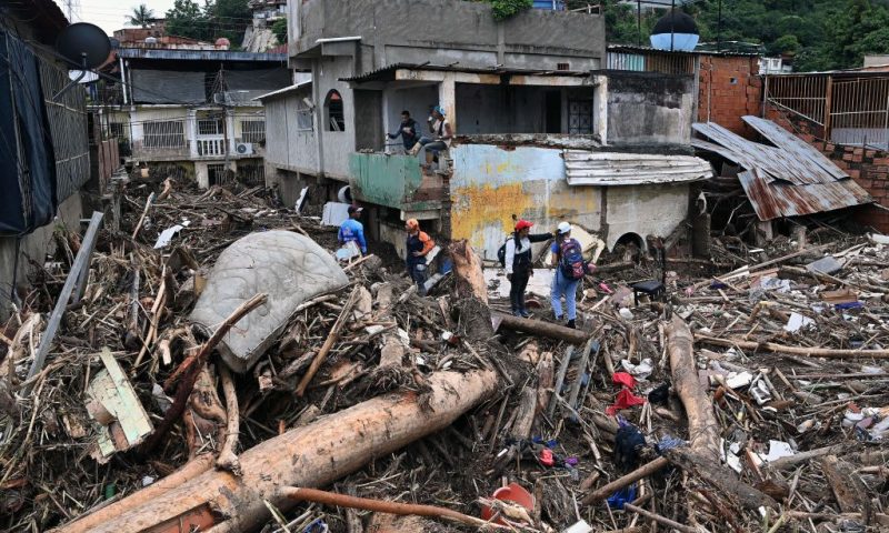 Rescuers and residents search through the rubble of destroyed houses for victims or survivors of a landslide during heavy rains in Las Tejerias, Aragua state, Venezuela, on October 9, 2022. - A landslide in central Venezuela left at least 22 people dead and more than 50 missing after heavy rains caused a river to overflow, Vice President Delcy Rodriguez said Sunday. (Photo by YURI CORTEZ / AFP) (Photo by YURI CORTEZ/AFP via Getty Images)