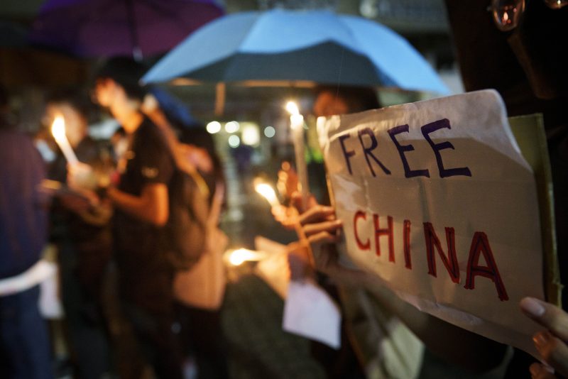 Student protesters hold up candles and placards during a commemoration for victims of a recent Urumqi apartment deadly fire blamed on the rigid anti-virus measures, held in Kuala Lumpur, Malaysia, Tuesday, Nov. 29, 2022. On Tuesday, about a dozen people gathered at the University of Malaya, chanting against virus restrictions and holding up sheets of paper with critical slogans. (AP Photo/Vincent Thian)