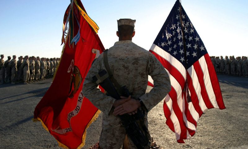 This photo released by the US Marine corps 11 November 2006 shows, a US Marine with the Hawaii-based 2nd Battalion, 3rd Marine Regiment standing behind the American and Marine Corps flags during the ceremony honoring the Marine Corps' 231st birthday at the Haditha Dam, in Iraq's al -Anbar Province, west of Baghdad, 10 November, 2006. The US government will offer a reward up to 50,000 dollars to help find a soldier kidnapped in Baghdad, the military said 11 November 2006. Specialist Ahmed Qusai al-Taie was abducted outside Baghdad's heavily fortified Green Zone on October 23. Taie, 41, is an American of Iraqi descent who moved to the United States as a teenager and joined the army reserve in December 2004. AFP PHOTO/HO/CPL. LUKE BLOM (Photo by Luke BLOM / USMC / AFP) (Photo by LUKE BLOM/USMC/AFP via Getty Images)