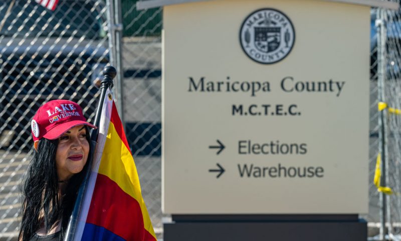 A right wing activist wearing a 'LAKE FOR GOVERNOR' hat stands on the sidewalk in protest of the election process in front of the Maricopa County Tabulation and Election Center on November 14, 2022 in Phoenix, Arizona. Ballots continue to be counted in Maricopa County following the November 8 midterm election as officials push back against conspiracy theories claiming the process is being delayed. (Photo by Jon Cherry/Getty Images)