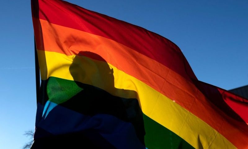 TOPSHOT - A commuity members silhouette is seen through a Pride flag while paying their respects to the victims of the mass shooting at Club Q, an LGBTQ nightclub, in Colorado Springs, Colorado, on November 20, 2022. - At least five people were killed and 18 wounded in a mass shooting at an LGBTQ nightclub in the US city of Colorado Springs, police said on November 20, 2022. (Photo by Jason Connolly / AFP) (Photo by JASON CONNOLLY/AFP via Getty Images)
