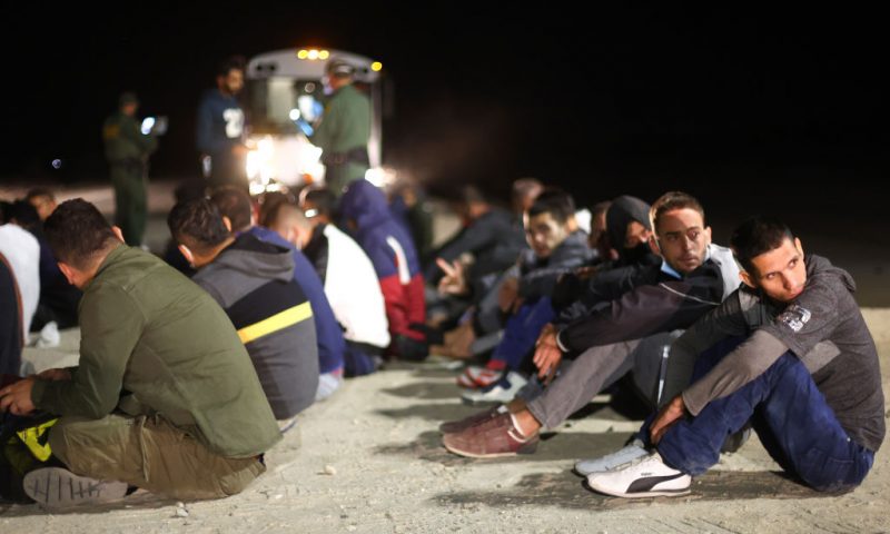 Immigrants wait to board a U.S. Border Patrol bus to be taken for processing after crossing the border from Mexico on May 23, 2022 in Yuma, Arizona. Title 42, the controversial pandemic-era border policy enacted by former President Trump, which cites COVID-19 as the reason to rapidly expel asylum seekers at the U.S. border, was set to officially expire on May 23rd. A federal judge in Louisiana delivered a ruling May 20th blocking the Biden administration from lifting Title 42. (Photo by Mario Tama/Getty Images)