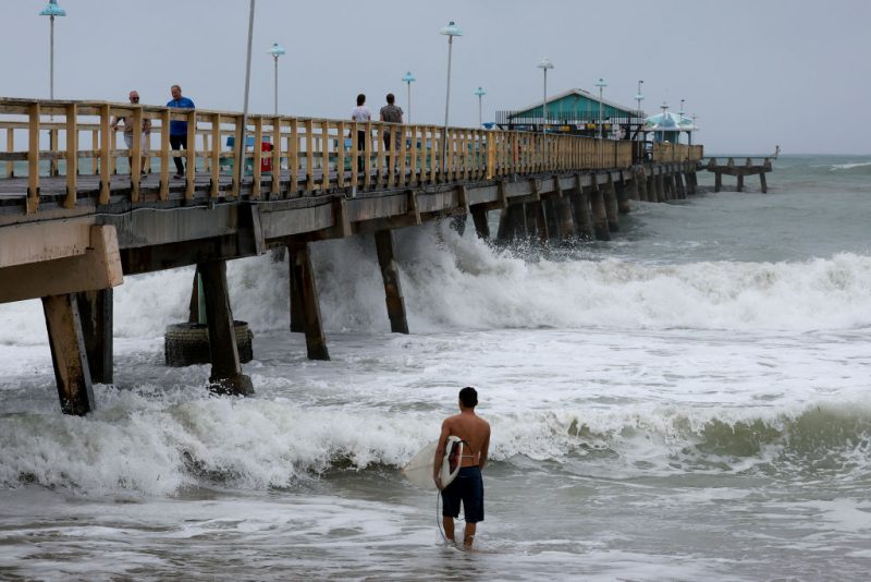 LAUDERDALE-BY-THE-SEA, FLORIDA - NOVEMBER 09: A surfer enters the water near Anglin's Fishing Pier as the ocean is whipped up by Tropical Storm Nicole on November 09, 2022 in Lauderdale-By-The-Sea, Florida. Tropical Storm Nicole could become a Category 1 hurricane before hitting Florida’s east coast by early Thursday. (Photo by Joe Raedle/Getty Images)