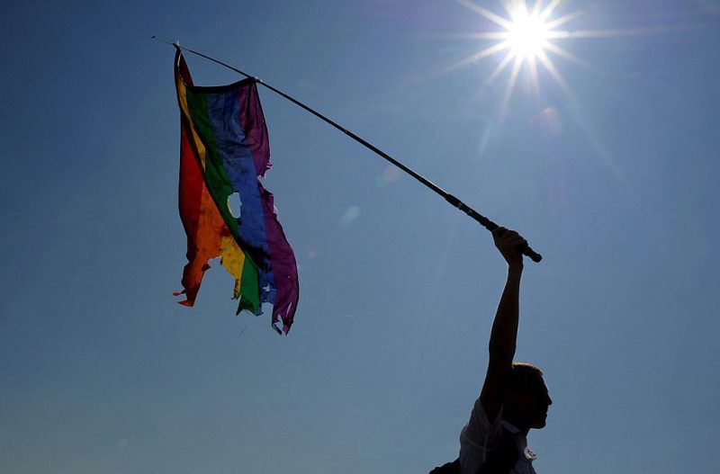 A gay rights activist waves a damaged rainbow flag during a gay pride in St. Petersburg on July 26, 2014. AFP PHOTO / OLGA MALTSEVA        (Photo credit should read OLGA MALTSEVA/AFP via Getty Images)