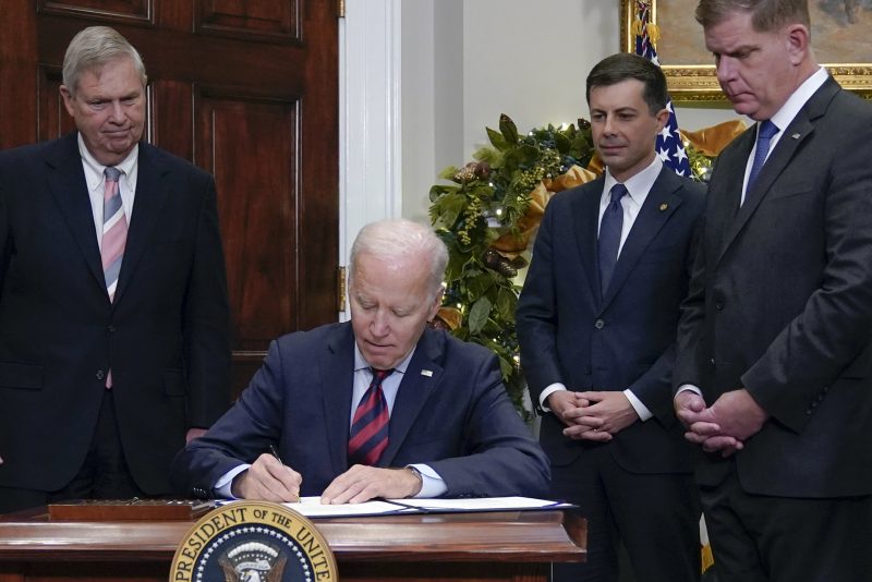 President Joe Biden signs H.J.Res.100, a bill that aims to avert a freight rail strike, in the Roosevelt Room at the White House, Friday, Dec. 2, 2022, in Washington. Biden is joined by from left, Agriculture Secretary Tom Vilsack, Transportation, Secretary Pete Buttigieg and Secretary of Labor Marty Walsh. (AP Photo/Manuel Balce Ceneta)