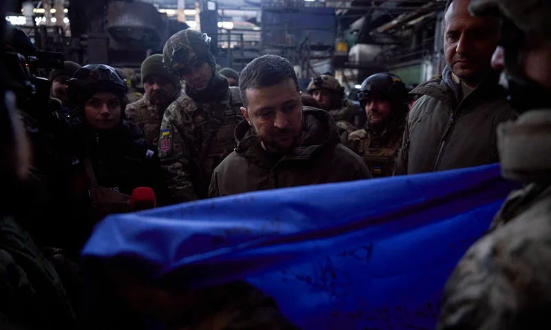 In this photo provided by the Ukrainian Presidential Press Office, Ukrainian President Volodymyr Zelenskyy, signs a Ukraine national flag, at the site of the heaviest battles with the Russian invaders in Bakhmut, Ukraine, Tuesday, Dec. 20, 2022. (Ukrainian Presidential Press Office via AP)