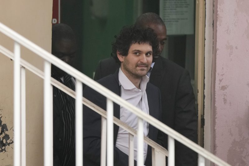 FTX founder Sam Bankman-Fried, is escorted from the Magistrate Court in Nassau, Bahamas, Wednesday, Dec. 21, 2022, after agreeing to be extradited to the U.S. (AP Photo/Rebecca Blackwell)