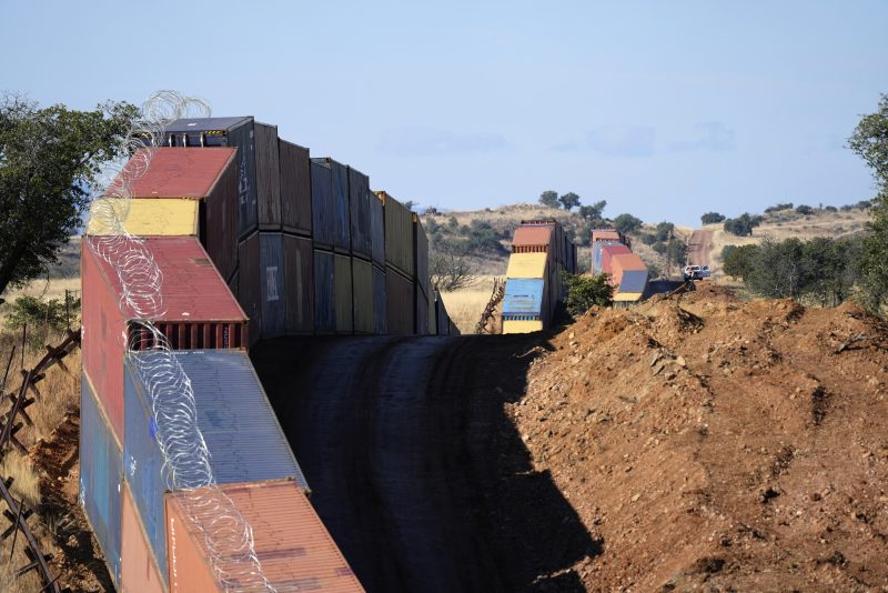 FILE - A long row of double-stacked shipping containers provide a new wall between the United States and Mexico in the remote section area of San Rafael Valley, Ariz., Thursday, Dec. 8, 2022. Arizona Gov. Doug Ducey will take down a makeshift wall made of shipping containers at the Mexico border, settling a lawsuit and political tussle with the U.S. government over trespassing on federal lands. (AP Photo/Ross D. Franklin, File)