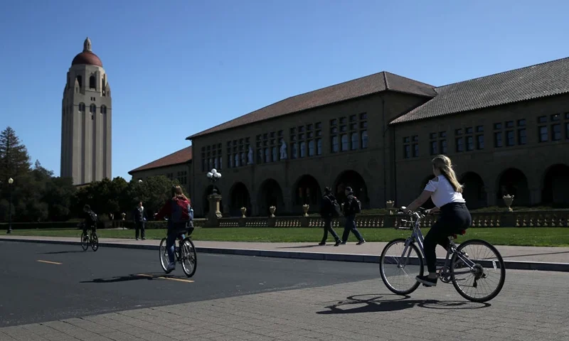Cyclists ride by Hoover Tower on the Stanford University campus on March 12, 2019 in Stanford, California. More than 40 people, including actresses Lori Loughlin and Felicity Huffman, have been charged in a widespread elite college admission bribery scheme. Parents, ACT and SAT administrators and coaches at universities including Stanford, Georgetown, Yale, and the University of Southern California have been charged. (Photo by Justin Sullivan/Getty Images)