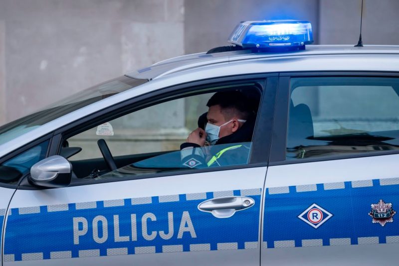 A police officer wearing a face mask patrols in his car during a protest by a few dozens of entrepreneurs in the center of Warsaw on March 31, 2020 against the insufficient governmental measures to help to reduce the negative effects of the coronavirus pandemic on the economical situation. - The demonstrators stayed in their cars to prevent violation of the ban of public meetings as they blocked one of Warsaw's main squares. Poland's government on March 31, 2020 further tightened measures taken to curb the spread of coronavirus, notably restricting the freedom of movement of youths, closing parks and hotels and limiting the number of shoppers. (Photo by Wojtek RADWANSKI / AFP) (Photo by WOJTEK RADWANSKI/AFP via Getty Images)