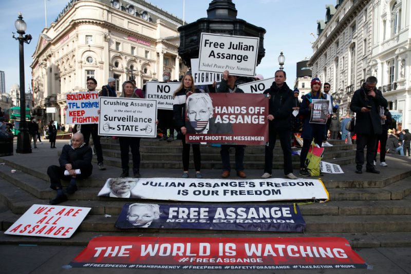 LONDON, ENGLAND - APRIL 17: Demonstrators hold a placards that say "Free Julian Assange" and "Hands Off Assange" at Piccadilly Circus on April 17, 2021 in London, England. Supporters of Wikileaks founder, Julian Assange, have spent this week protesting around the capital marking two years since he was removed from the Ecuadorean Embassy and sent to prison. (Photo by Hollie Adams/Getty Images)