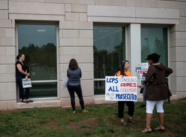 Protesters and activists hold signs as they stand outside a Loudoun County Public Schools (LCPS) board meeting in Ashburn, Virginia on October 12, 2021. - Loudoun county school board meetings have become tense recently with parents clashing with board members over transgender issues, the teaching of Critical Race Theory (CRT) and Covid-19 mandates. Recently tensions between groups of parents and the school board increased after parents say an allegedly transgender individual assaulted a girl at one of the schools. Earlier this month US Attorney General Merrick Garland directed federal authorities to hold strategy sessions in the next month with law enforcement to address the increasing threats targeting school board members, teachers and other employees in the nation's public schools. This in response to a request from the National School Boards Association asking US President Joe Biden for federal assistance to investigate and stop threats made over policies including mask mandates, likening the vitriol to a form of domestic terrorism. (Photo by Andrew CABALLERO-REYNOLDS / AFP) (Photo by ANDREW CABALLERO-REYNOLDS/AFP via Getty Images)