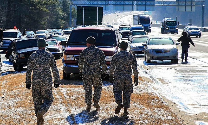 ATLANTA, GA - JANUARY 30: Army National Guardsmen walk along the Cumberland Boulevard exit ramp along I-75 North during the winter storm January 30, 2014 in Atlanta, Georgia. After drivers were stuck and abanonded their vehicles during a winter storm that snarled roads and highways thoughout the region, the roads have thawed and owners are begining to recvover their cars. (Photo by Daniel Shirey/Getty Images)