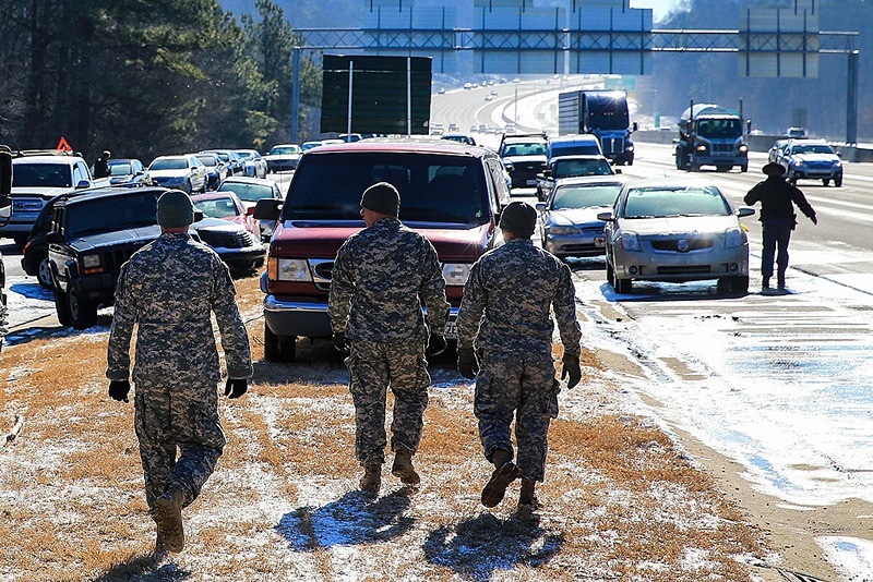 ATLANTA, GA - JANUARY 30: Army National Guardsmen walk along the Cumberland Boulevard exit ramp along I-75 North during the winter storm January 30, 2014 in Atlanta, Georgia. After drivers were stuck and abanonded their vehicles during a winter storm that snarled roads and highways thoughout the region, the roads have thawed and owners are begining to recvover their cars. (Photo by Daniel Shirey/Getty Images)
