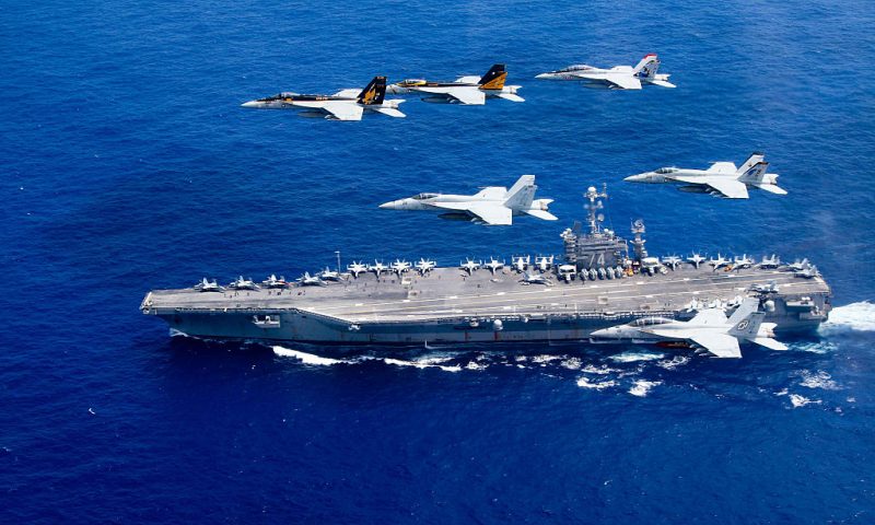 In this handout provided by the U.S. Navy, a combined formation of aircraft from Carrier Air Wing (CVW) 5 and Carrier Air Wing (CVW) 9 pass in formation above the Nimitz-class aircraft carrier USS John C. Stennis (CVN 74). The formation included F/A-18 Hornets from the Black Aces of Strike Fighter Squadron (VFA) 41, the Diamondbacks of Strike Fighter Squadron (VFA) 102, the Eagles of Strike Fighter Squadron (VFA) 115, the Royal Maces of Strike Fighter Squadron (VFA) 27, the Vigilantes of Strike Fighter Squadron (VFA) 151, and the Warhawks of Strike Fighter Squadron (VFA) 97. The Nimitz-class aircraft carriers USS John C. Stennis and USS Ronald Reagan (CVN 76) are conducting dual aircraft carrier strike group operations in the U.S. 7th Fleet area of operations in support of security and stability in the Indo-Asia-Pacific. (Photo by Lt. Steve Smith/U.S. Navy via Getty Images)