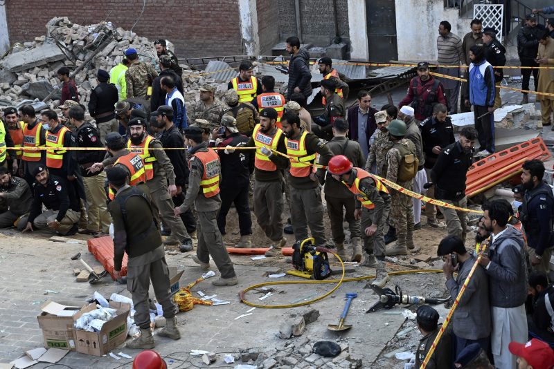 Security officials and rescue workers gather at the site of suicide bombing, in Peshawar, Pakistan, Monday, Jan. 30, 2023. A suicide bomber struck Monday inside a mosque in the northwestern Pakistani city of Peshawar, killing multiple people and wounding scores of worshippers, officials said. (AP Photo/Zubair Khan)