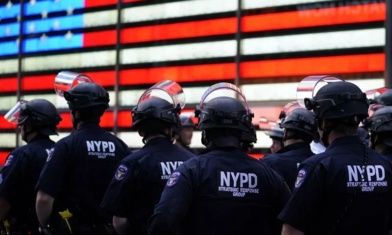 OPSHOT - NYPD police officers watch demonstrators in Times Square on June 1, 2020, during a "Black Lives Matter" protest. - New York's mayor Bill de Blasio today declared a city curfew from 11:00 pm to 5:00 am, as sometimes violent anti-racism protests roil communities nationwide. Saying that "we support peaceful protest," De Blasio tweeted he had made the decision in consultation with the state's governor Andrew Cuomo, following the lead of many large US cities that instituted curfews in a bid to clamp down on violence and looting. (Photo by TIMOTHY A. CLARY / AFP) (Photo by TIMOTHY A. CLARY/AFP via Getty Images)
