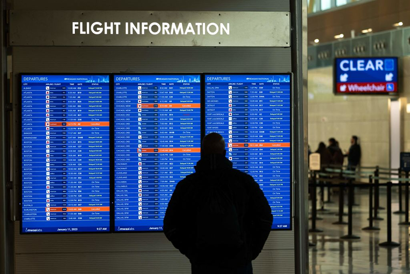 A traveler looks at a flight information display listing cancelled and delayed flights due to an FAA outage that grounded flights across the US at Ronald Reagan Washington National Airport in Arlington, Virginia, January 11, 2023. - The US Federal Aviation Authority said Wednesday that normal flight operations "are resuming gradually" across the country following an overnight systems outage that grounded departures. (Photo by SAUL LOEB / AFP) (Photo by SAUL LOEB/AFP via Getty Images)