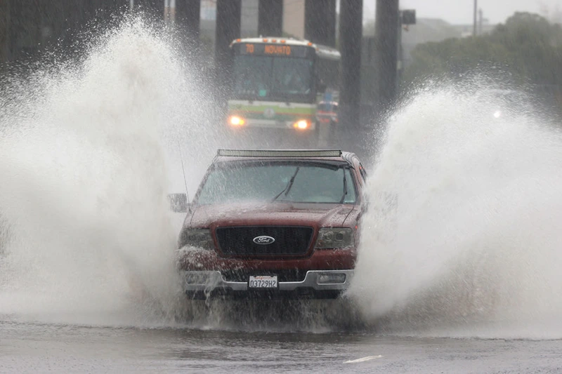 Water kicks up as a truck drives on a flooded street on October 24, 2021 in Mill Valley, California. A category 5 atmospheric river is bringing heavy precipitation, high winds and power outages to the San Francisco Bay Area. The storm is expected to bring anywhere between 2 to 5 inches of rain to many parts of the area. (Photo by Justin Sullivan/Getty Images)