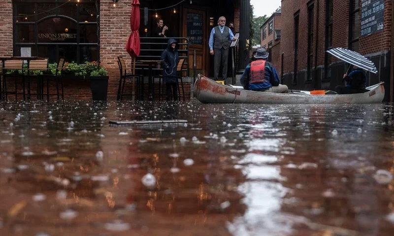 The bar manager at the Union Street pub speaks to Keith Harmon (L) and Heidi DeuPree, as he takes an order while they paddle through flood water in a canoe in Old Town Alexandria, Virginia, on October 29, 2021. - The US National Weather Service has implemented a flood watch for Maryland, Washington, DC, and parts of Virginia. Flooding from heavy rain hit parts of the US East Coast on October 29, particularly the area around Washington, with potential for some of the worst damage in decades. (Photo by ANDREW CABALLERO-REYNOLDS / AFP) (Photo by ANDREW CABALLERO-REYNOLDS/AFP via Getty Images)