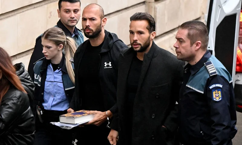 British-US former professional kickboxer and controversial influencer Andrew Tate (3rd R) and his brother Tristan Tate (2nd R) arrive handcuffed and escorted by police at a courthouse in Bucharest on January 10, 2023 for a court hearing on their appeal against pre-trial detention for alleged human trafficking, rape and forming a criminal group. (Photo by Daniel MIHAILESCU / AFP) (Photo by DANIEL MIHAILESCU/AFP via Getty Images)