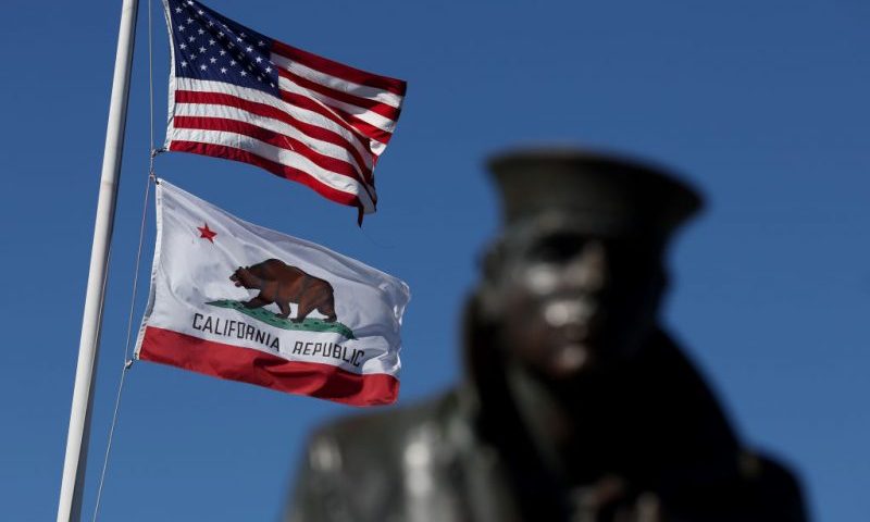 SAUSALITO, CALIFORNIA - OCTOBER 24: An American flag flies with the California State flag next to the Lone Sailor statue on October 24, 2022 in Sausalito, California. The State of California, currently the fifth largest economy in the world, is likely to overtake Germany as the fourth largest economy in the near future as the state's gross domestic product is continuing to rise with steady growth. (Photo by Justin Sullivan/Getty Images)