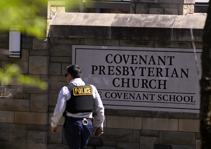 A police officer walks by an entrance to The Covenant School after a shooting in Nashville, Tenn. on Monday, March 27, 2023. (AP Photo/John Amis)
