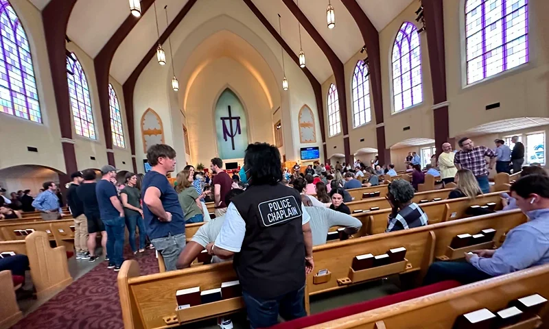 A police chaplain stands by as children from The Covenant School, a private Christian school in Nashville, Tenn., are taken to a reunification site at the Woodmont Baptist Church after a shooting at their school, on Monday, March, 27, 2023.