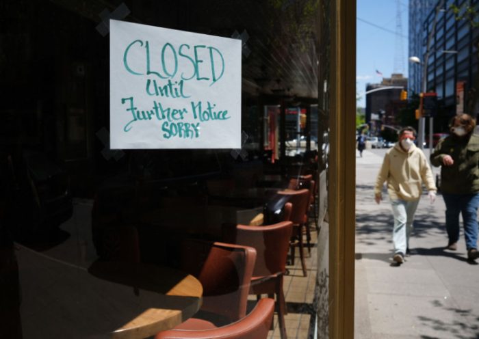 NEW YORK CITY- MAY 12: People walk through a shuttered business district in Brooklyn on May 12, 2020 in New York City. Across America, people are reeling from the loss of jobs and incomes as unemployment soars to historical levels following the COVID-19 outbreak. While some states are beginning to re-open slowly, many business are struggling to find a profit with the news restrictions and a population that is fearful of the contagious virus. (Photo by Spencer Platt/Getty Images)