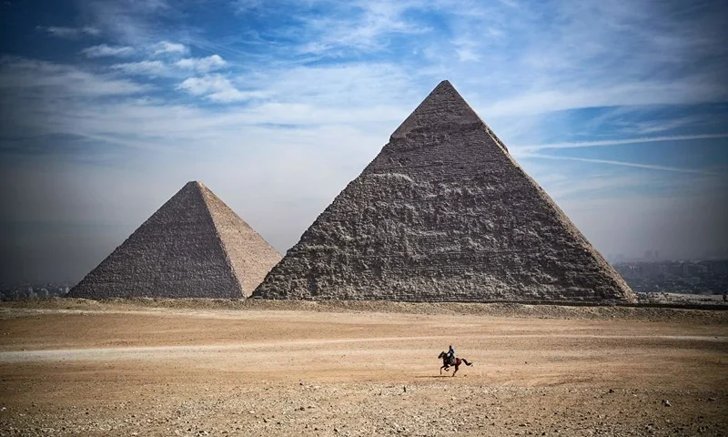 A man rides a horse in front of the pyramids of Khufu (Cheops) (L), Khafre (Chephren), at the Giza pyramids necropolis on the southwestern outskirts of the Egyptian capital Cairo, on January 26, 2021. (Photo by Anne-Christine POUJOULAT / AFP) (Photo by ANNE-CHRISTINE POUJOULAT/AFP via Getty Images)