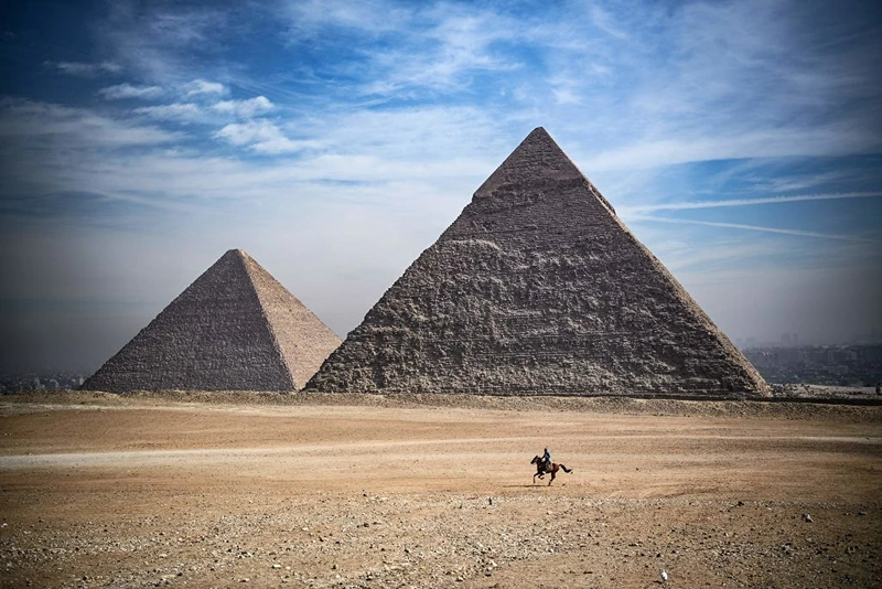 A man rides a horse in front of the pyramids of Khufu (Cheops) (L), Khafre (Chephren), at the Giza pyramids necropolis on the southwestern outskirts of the Egyptian capital Cairo, on January 26, 2021. (Photo by Anne-Christine POUJOULAT / AFP) (Photo by ANNE-CHRISTINE POUJOULAT/AFP via Getty Images)