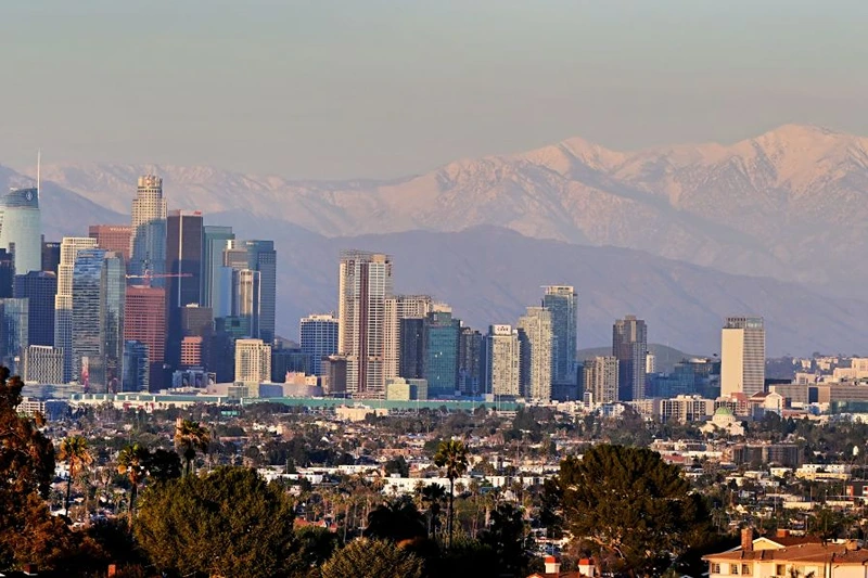 Snow-capped mountains are seen in the distance behind the downtown skyline on March 2, 2023 in Los Angeles, California where a new cold system brought hail and snow to unusually low elevations for the mountains in Southern California. (Photo by Frederic J. BROWN / AFP) (Photo by FREDERIC J. BROWN/AFP via Getty Images)