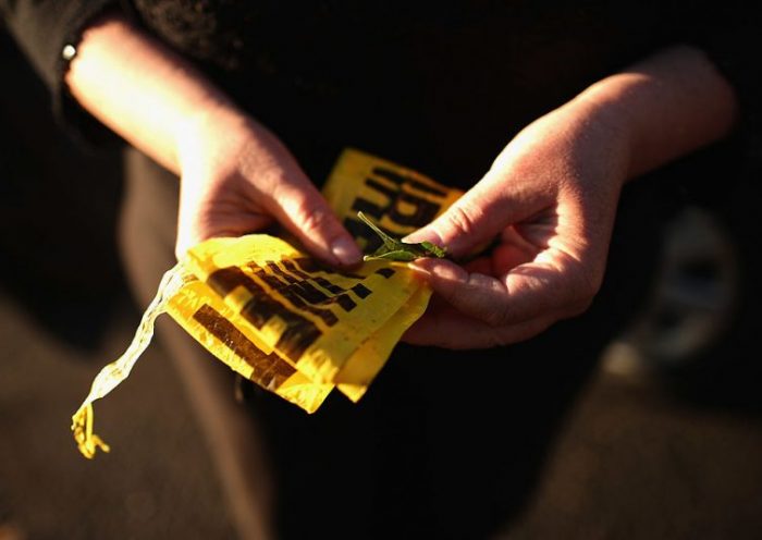 Denise Toepel of Denver holds discarded crime scene tape that she will keep as a memento while visiting a makeshift memorial across the street from the Century 16 movie theater July 21, 2012 in Aurora, Colorado. A day earlier a gunman killed 12 people and injured 59 during an early morning screening of 'The Dark Knight Rises.' Police in Aurora, a suburb of Denver, say they have a suspect James Holmes, 24, in custody. Toepel, a demographics surveyor, gathers audience reactions from inside theaters during movie premieres. "It's a fun job," she said. "But it suddenly became a little hairy." She hopes they tear down the theater in the wake of the mass shooting. "Who could ever feel safe there again?" (Photo by Chip Somodevilla/Getty Images)