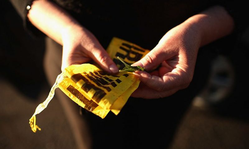 Denise Toepel of Denver holds discarded crime scene tape that she will keep as a memento while visiting a makeshift memorial across the street from the Century 16 movie theater July 21, 2012 in Aurora, Colorado. A day earlier a gunman killed 12 people and injured 59 during an early morning screening of 'The Dark Knight Rises.' Police in Aurora, a suburb of Denver, say they have a suspect James Holmes, 24, in custody. Toepel, a demographics surveyor, gathers audience reactions from inside theaters during movie premieres. "It's a fun job," she said. "But it suddenly became a little hairy." She hopes they tear down the theater in the wake of the mass shooting. "Who could ever feel safe there again?" (Photo by Chip Somodevilla/Getty Images)