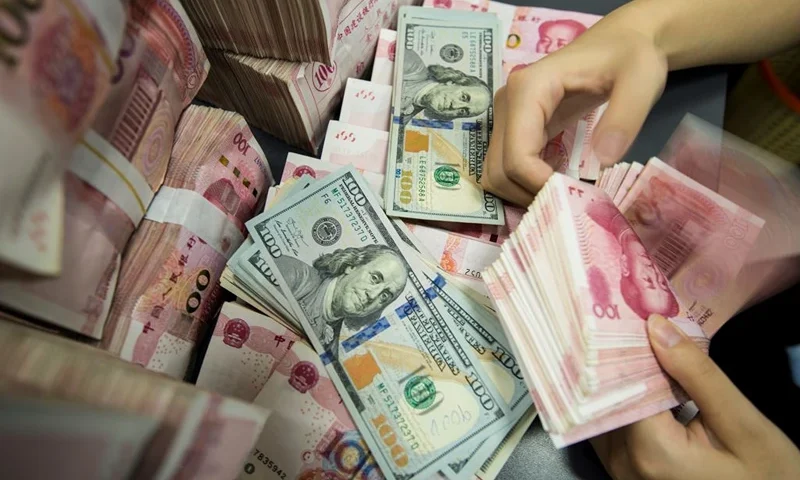 A Chinese bank employee counts 100-yuan notes and US dollar bills at a bank counter in Nantong in China's eastern Jiangsu province on August 28, 2019. - China's currency slid on August 26 to its weakest point in more than 11 years as concerns over the US trade war and the potential for global recession weighed on markets. (Photo by STR / AFP) / China OUT (Photo by STR/AFP via Getty Images)