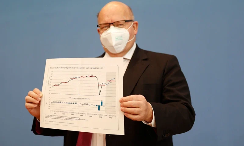 German Economy Minister Peter Altmaier holds a paper with a graph of the gross domestic product (GDP) as he arrives for a press conference to present the annual economic report for Germany, in Berlin on January 27, 2021. - The German government said on January 27 it expected Europe's top economy to grow by three percent this year, less than previously forecast, as longer virus shutdowns slow the pandemic recovery. (Photo by Odd ANDERSEN / various sources / AFP) (Photo by ODD ANDERSEN/POOL/AFP via Getty Images)