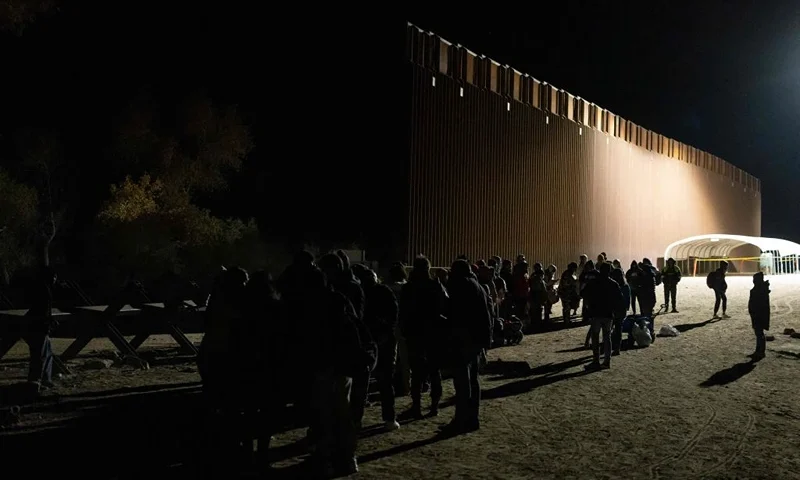 Asylum-seekers line up to be processed by US Customs and Border Patrol agents at a gap in the US-Mexico border fence near Somerton, Arizona, on December 26, 2022. - The United States is seeing a rising number of asylum-seekers turning themselves in at the US-Mexico border in anticipation of the lifting of Title 42, a pandemic-era policy used to bar migrants from entering the US. (Photo by Rebecca NOBLE / AFP) (Photo by REBECCA NOBLE/AFP via Getty Images)