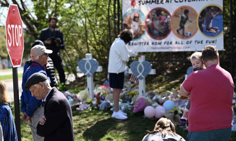 People pay their respects at a makeshift memorial for victims at the Covenant School building at the Covenant Presbyterian Church following a shooting, in Nashville, Tennessee, on March 29, 2023. - A heavily armed former student killed three young children and three staff in what appeared to be a carefully planned attack at a private elementary school in Nashville on March 27, before being shot dead by police. Chief of Police John Drake named the suspect as Audrey Hale, 28, who the officer later said identified as transgender. (Photo by Brendan SMIALOWSKI / AFP) (Photo by BRENDAN SMIALOWSKI/AFP via Getty Images)