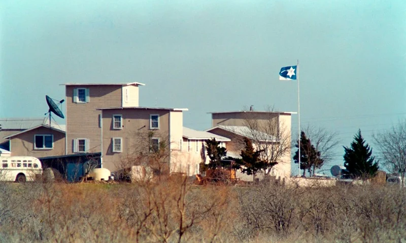 A cult flag flies over the Branch Davidian compound in Waco on March 08, 1993 . After a shootout in Waco in 1993 that killed four federal agents and six members of the Branch Davidian religious sect, authorities negotiated with cult leader David Koresh for 51 days. On the final day, 19 April 1993, a few hours after a government tank rammed the cult's wooden fortress, the siege ended in a fiery blaze, killing Koresh and 80 of his followers. (Photo by BOB STRONG / AFP) (Photo by BOB STRONG/AFP via Getty Images)
