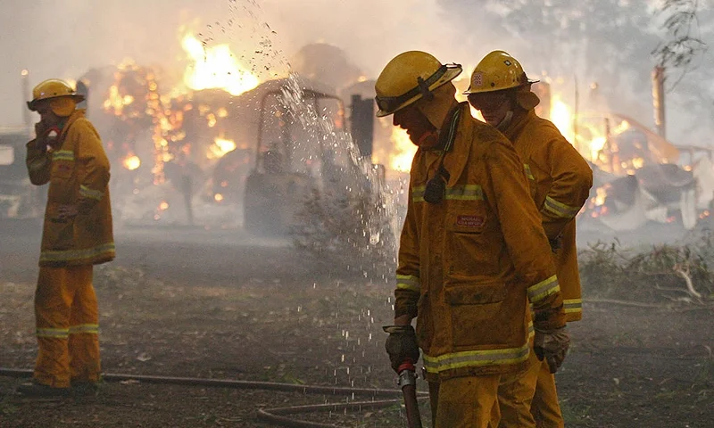 Country Fire Authority (CFA) volunteers pack away their hose as a barn burns in the background after they managed to save the house close to Labertouche, some 125 kilometres west of Melbourne, on February 7, 2009. More than 40 blazes raged across two states as a once-in-a-century heatwave pushed the mercury as high as 46 degrees Celsius (115 Fahrenheit) with fire bans in place across much of the south-east, with conditions said to be the worst since the Ash Wednesday wildfires of 1983, which killed 75 people and razed 2,500 homes. AFP PHOTO/William WEST (Photo by WILLIAM WEST/AFP via Getty Images)