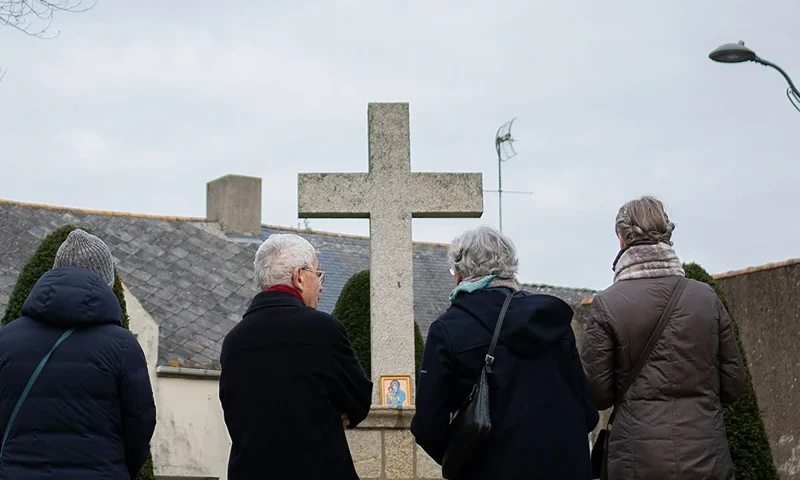 Christians pray in front of a cross in La Baule-Escoublac, western France, on February 23, 2022. - A Catholic group "La France qui prie" (France who prays) has called on fellow faithfuls to perform public prayers at Catholic calvaries, statues and churches everywhere in France to entrust the country to the Virgin Mary, following an initiative launched November 2021 in Austria in connection with the health crisis and restrictions imposed to fight against the spread of Covid 19. (Photo by LOIC VENANCE/AFP via Getty Images)