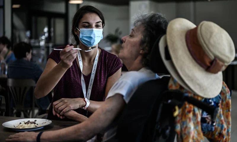 This picture taken on September 9, 2020 shows a volunteer (L) attending an Alzheimers patients during lunch at the restaurant of the village Landais Alzheimer site for Alzheimers patients in Dax, southwestern France. (Photo by Philippe LOPEZ / AFP) (Photo by PHILIPPE LOPEZ/AFP via Getty Images)