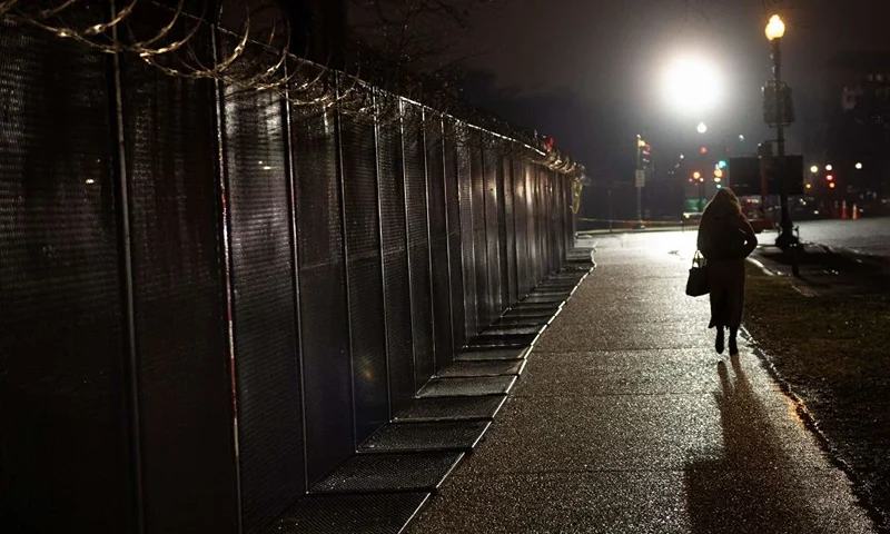 A woman walks past a razor wire topped security fence after the second day of former US President Donald Trump's impeachment trial before the Senate on Capitol Hill February 10, 2021, in Washington, DC. - Impeachment prosecutors aired terrifying, never-before-seen footage of senior US politicians fleeing for their lives during the January assault on Congress by Donald Trump supporters on day two of the former president's Senate trial. (Photo by Brendan Smialowski / AFP) (Photo by BRENDAN SMIALOWSKI/AFP via Getty Images)